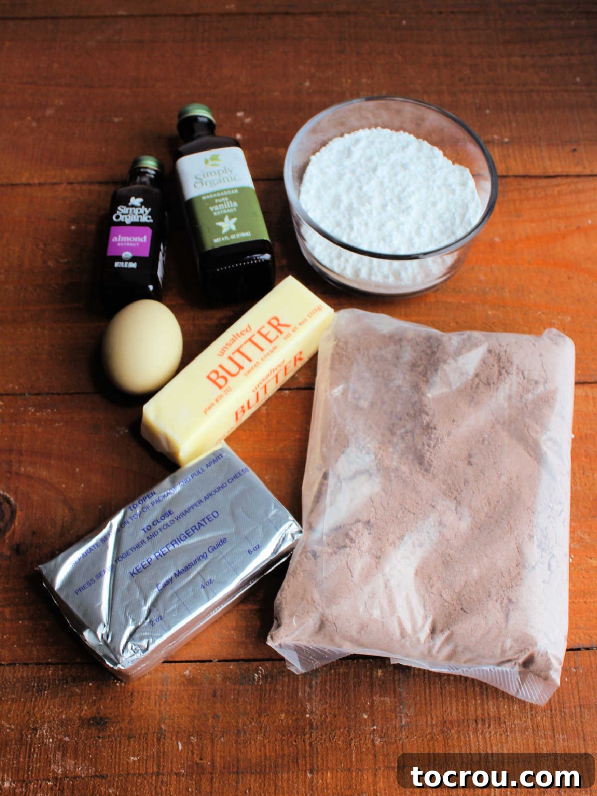 Ingredients including chocolate cake mix, cream cheese, butter, egg, vanilla, almond extract, and powdered sugar ready to be made into cookies.