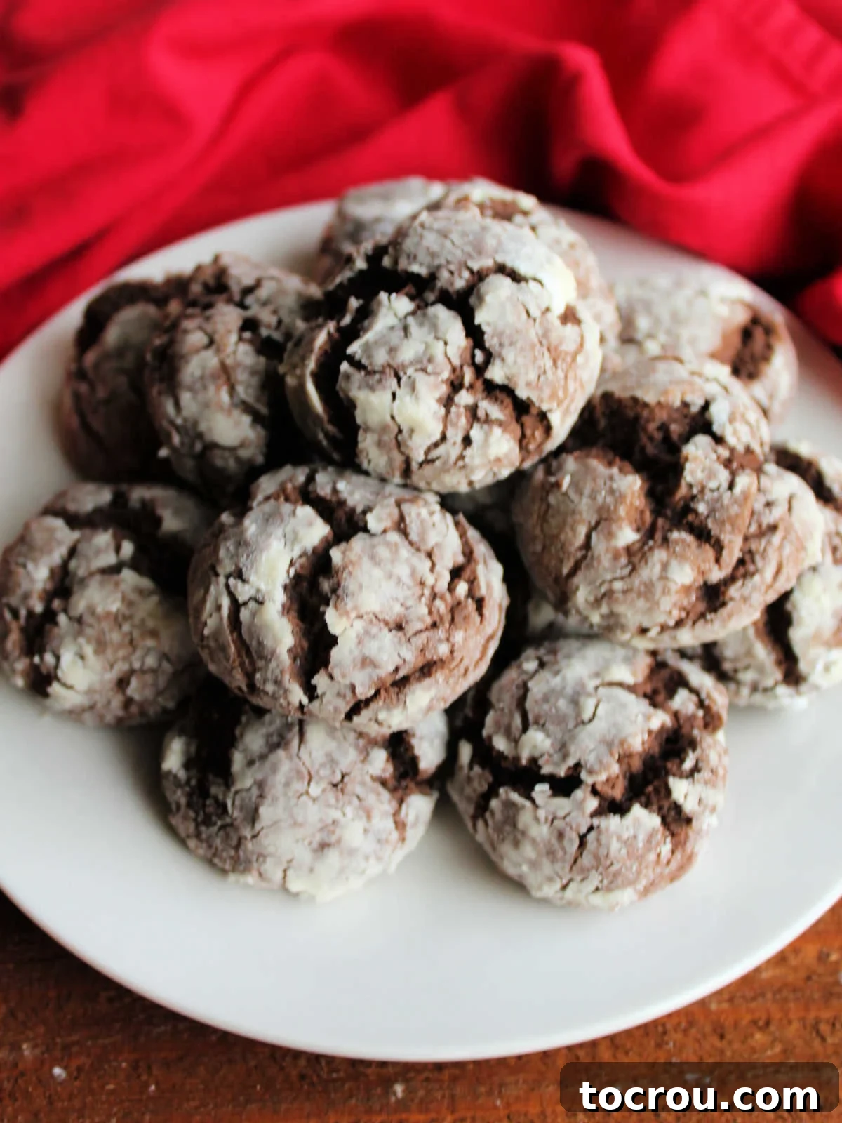 Plate of chocolate gooey butter cookies with rich chocolate center and crackled powdered sugar exterior, ready to eat.