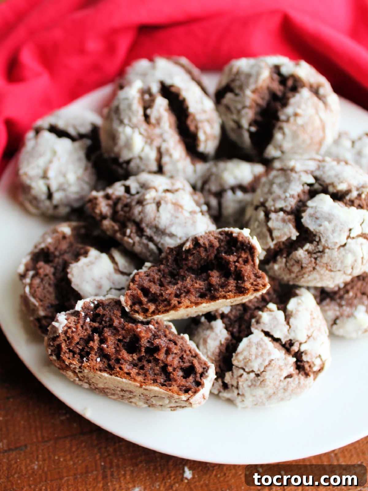 Platter of chocolate cake mix crinkle cookies with one broken in half, showing soft fudgy center.