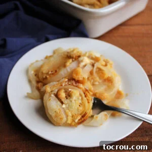 Plate of cheesy onion casserole with softened rings of onions and buttery cracker topping, ready to eat.