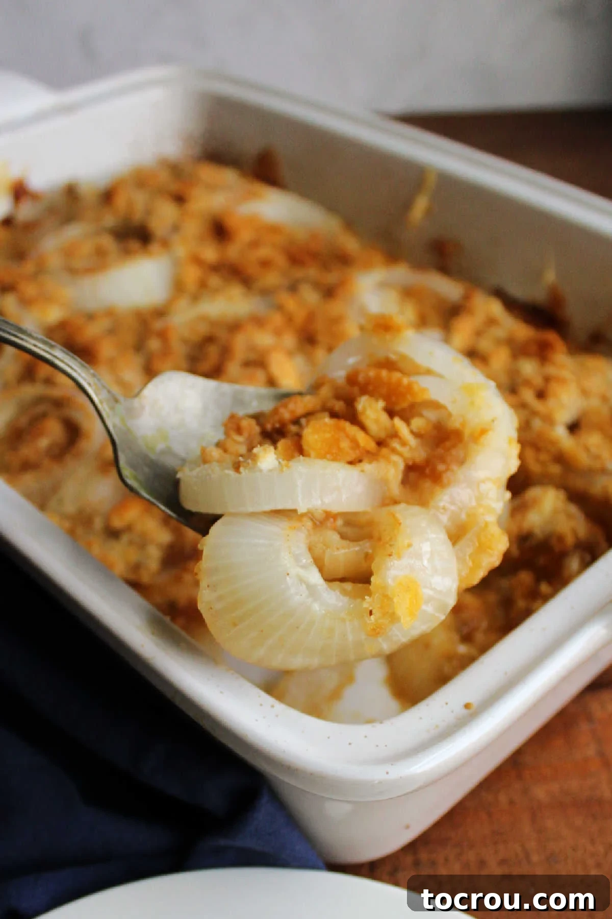 Large serving spoon filled with onion casserole, ready to go on dinner plate.