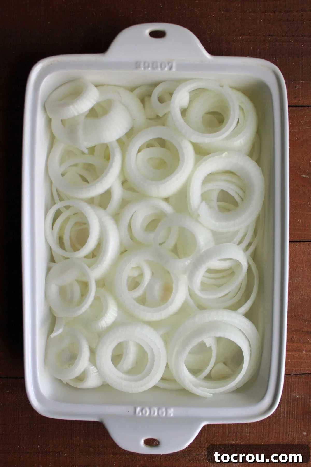 Sliced rings of sweet onion in casserole dish.