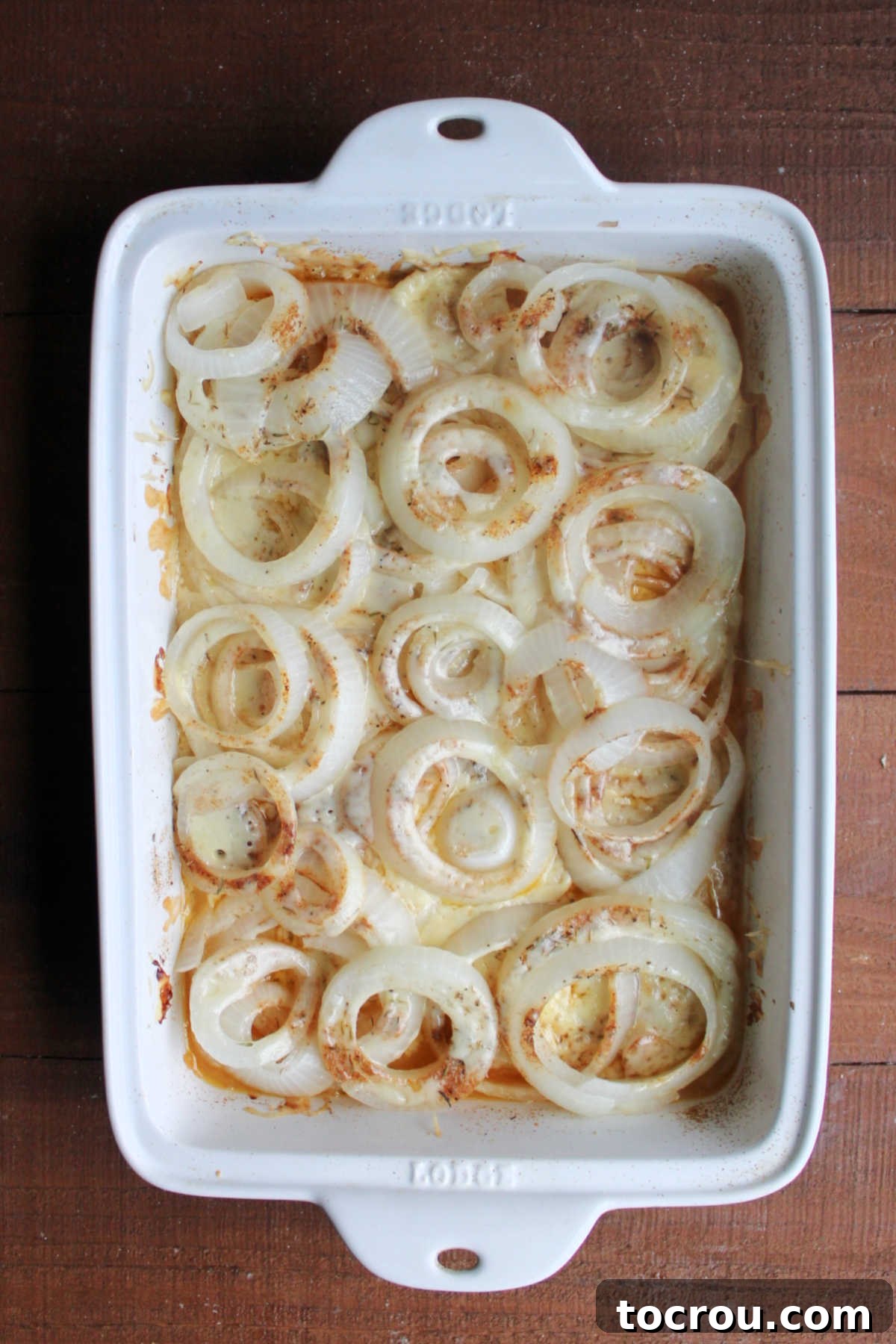 Partially baked casserole showing softened onions and melted cheese.