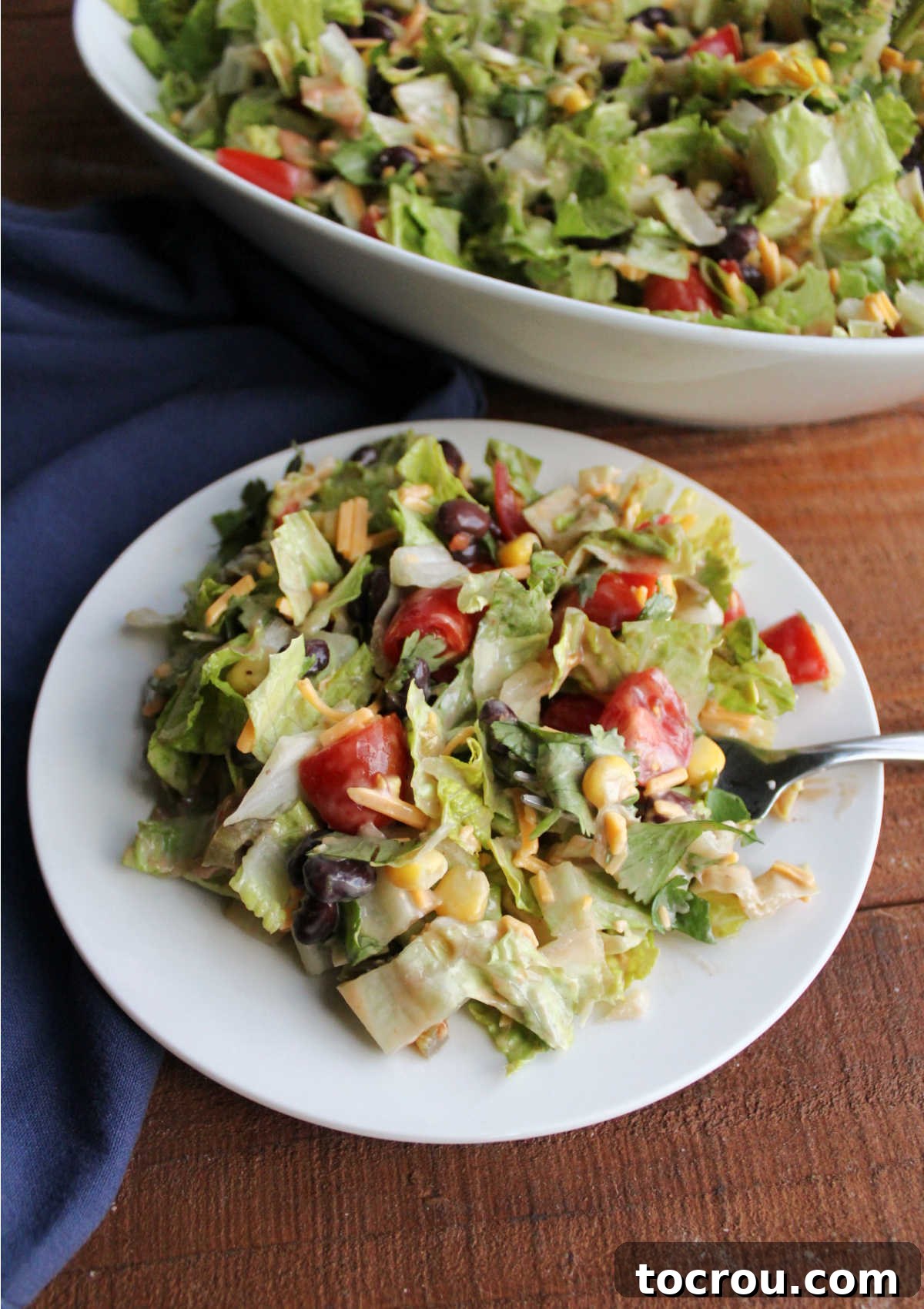 Served cowboy salad on small plate with remaining salad bowl in the background.