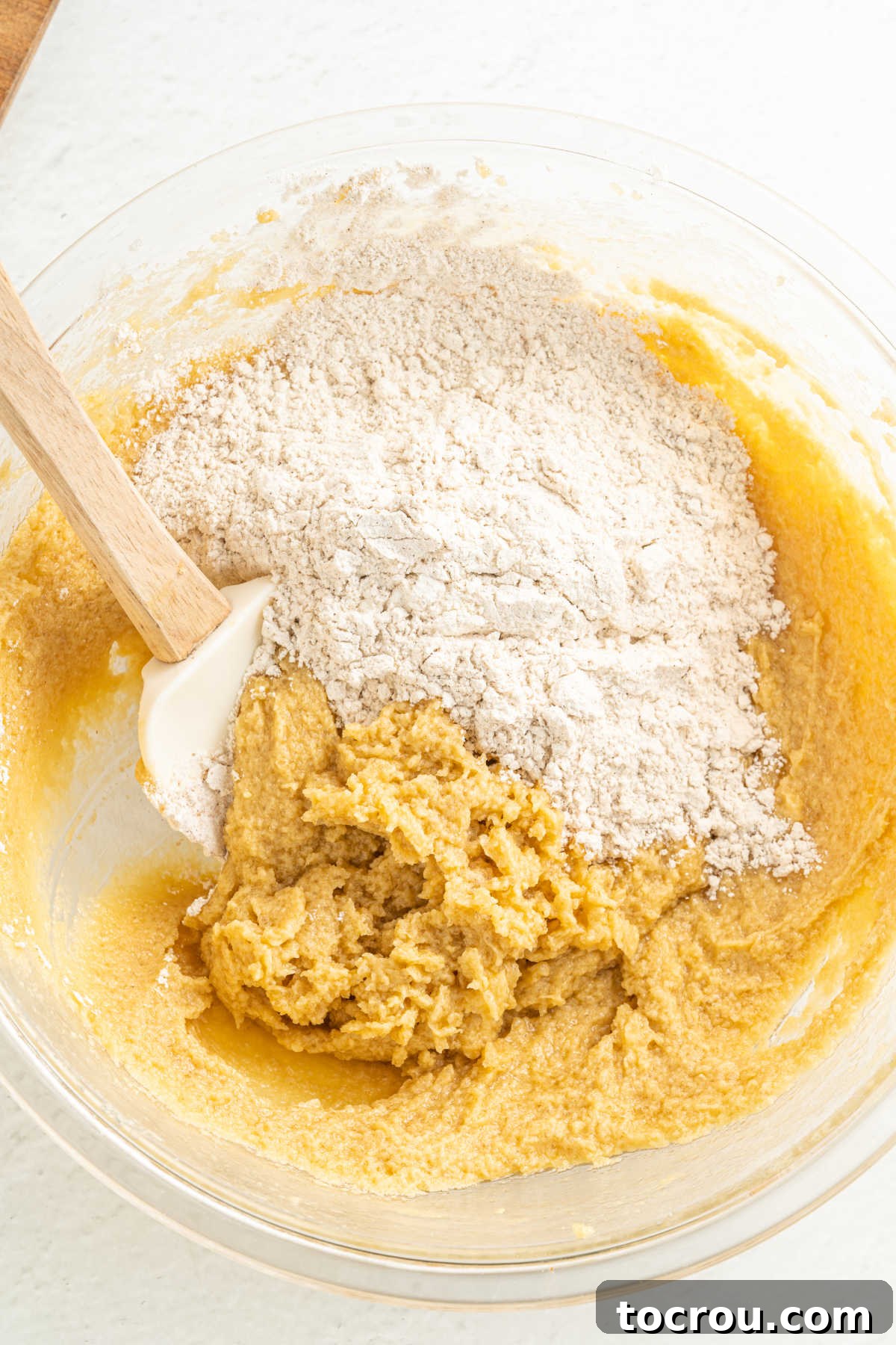 Mixing flour mixture into butter mixture to make cookie dough.