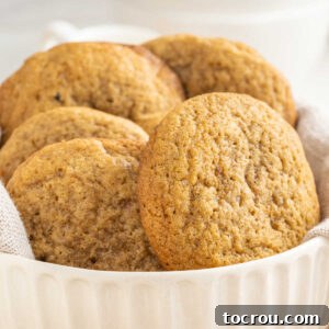 Close up of a white bowl filled with large tan chai spiced cookies, showing their soft texture.