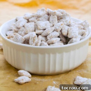 A vibrant bowl of caramel puppy chow with Chex cereal coated in caramel and powdered sugar, ready to be served.
