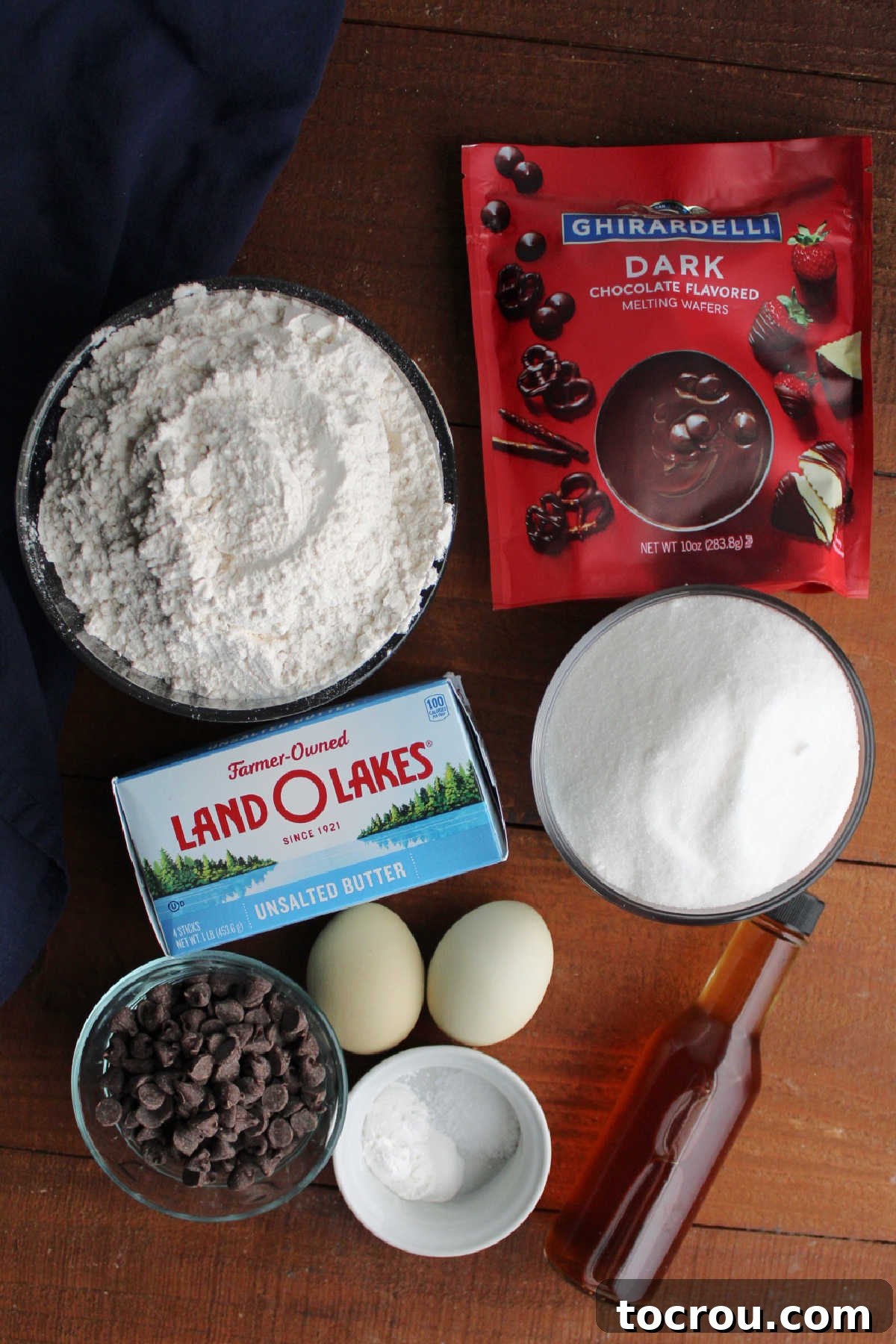 Sweet Vanilla Paw Delights 4 All the essential ingredients for making vanilla paw print cookies laid out on a kitchen counter: softened butter, granulated sugar, all-purpose flour, large eggs, baking powder, salt, vanilla extract, and two types of chocolate for decoration.