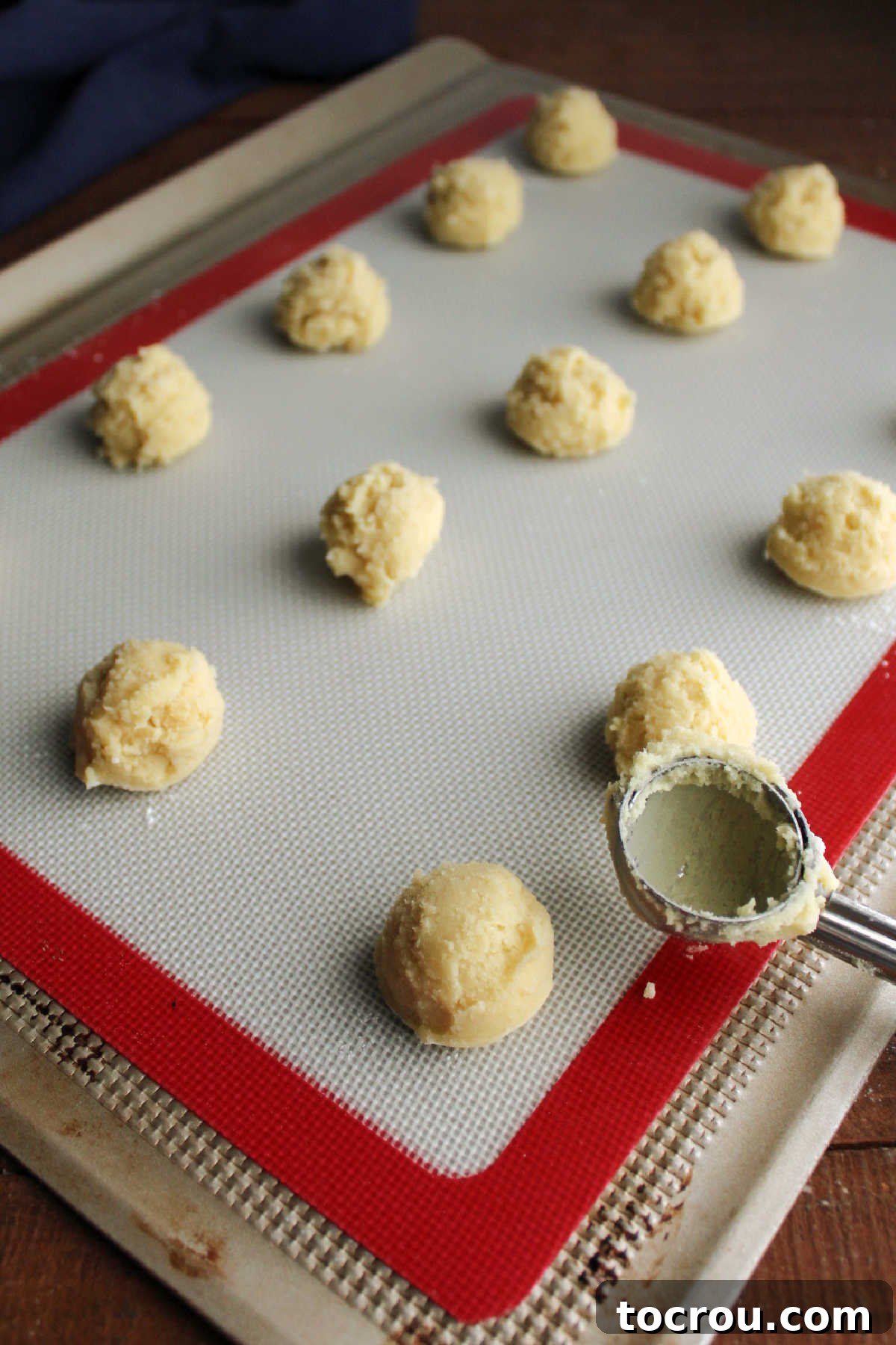 Sweet Vanilla Paw Delights 6 Small, uniform scoops of chilled vanilla cookie dough meticulously arranged on a baking sheet lined with parchment paper, prepared for immediate oven baking.
