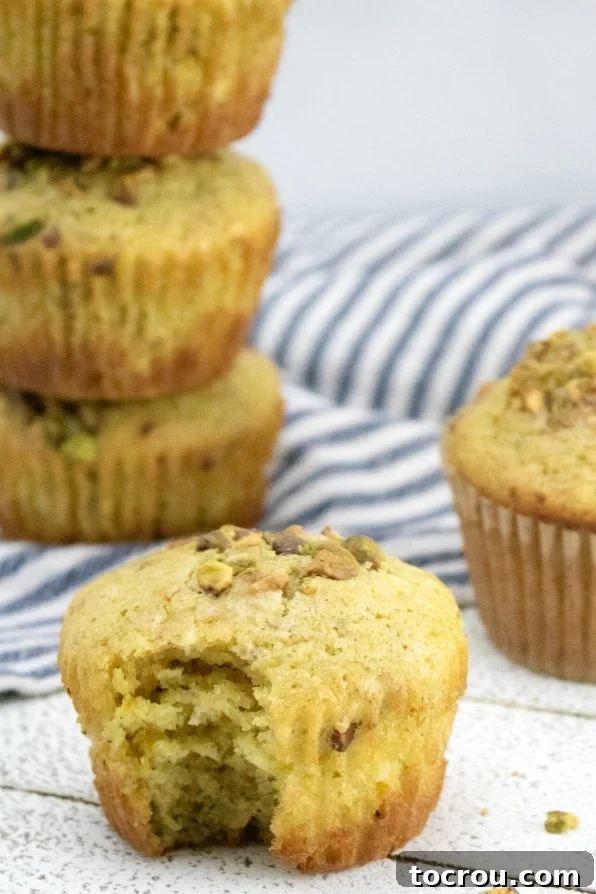 Stack of freshly baked orange pistachio muffins, perfectly golden and inviting.