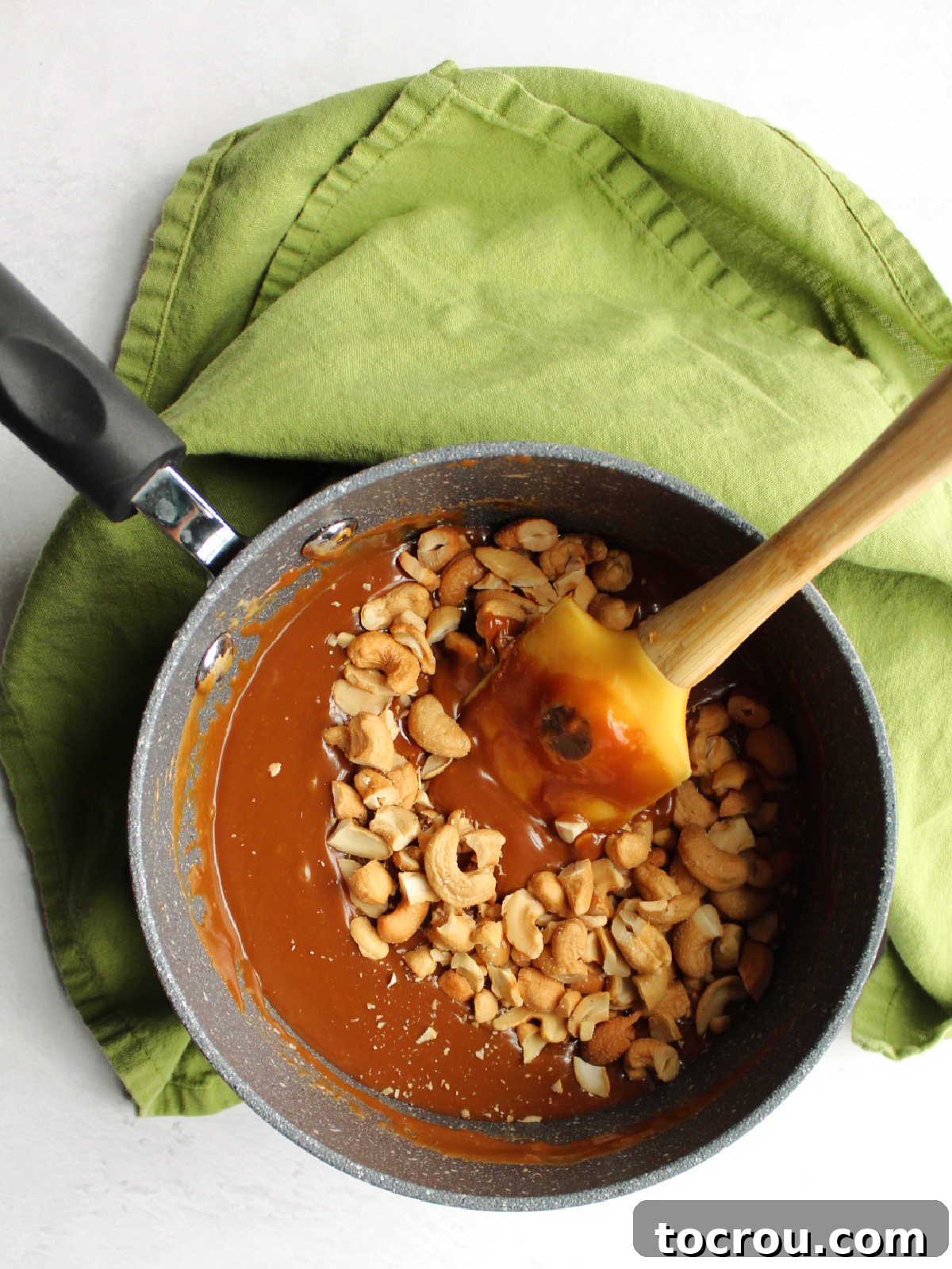 Melted Caramel with Cashews Saucepan filled with melted caramel and cashew pieces.