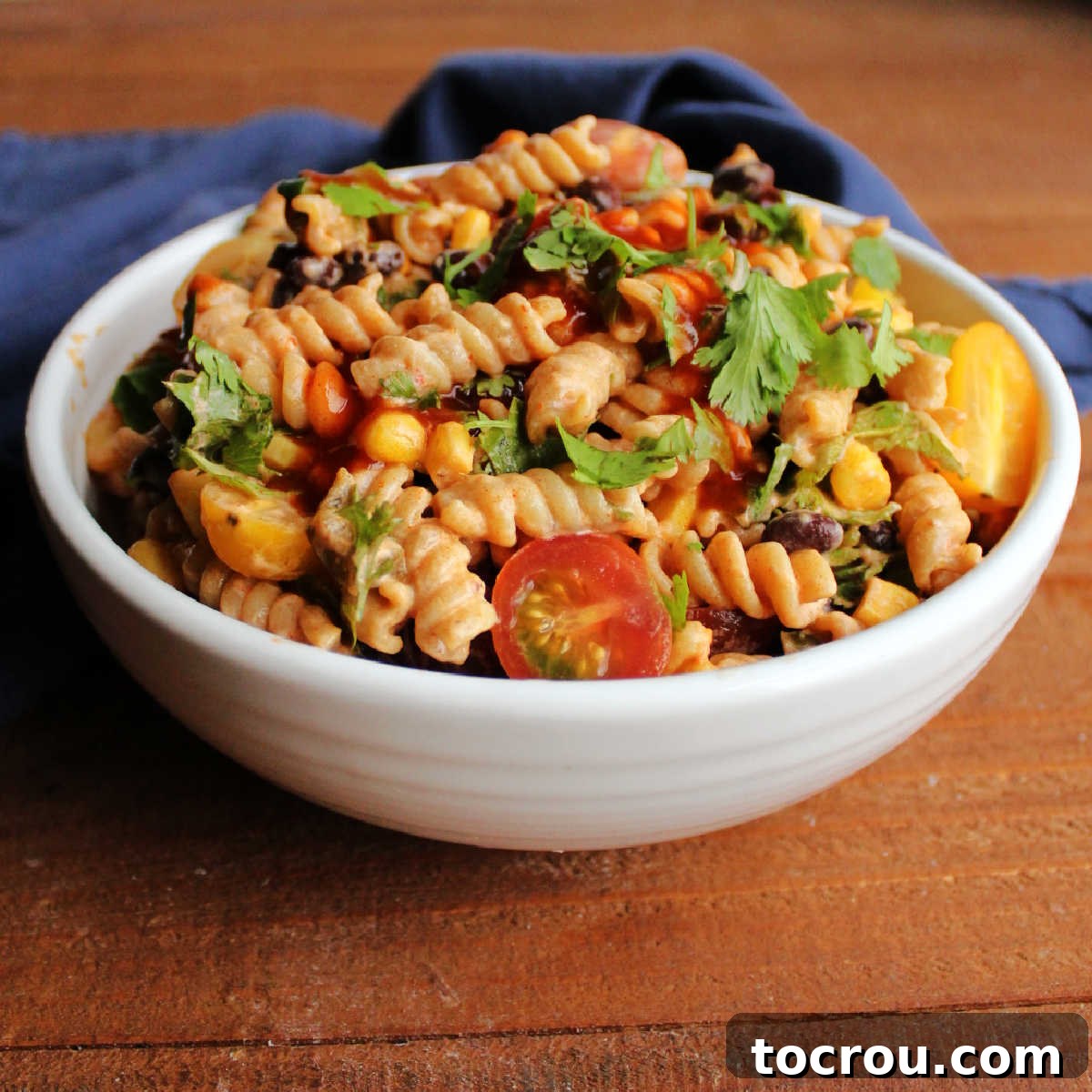 Vibrant Enchilada Pasta Salad – A Summer Favorite A large serving bowl filled to the brim with colorful Enchilada Pasta Salad, featuring red enchilada sauce, tender pasta, juicy tomatoes, sweet corn, black beans, vibrant jalapenos, and fresh cilantro, perfectly garnished and ready to serve.