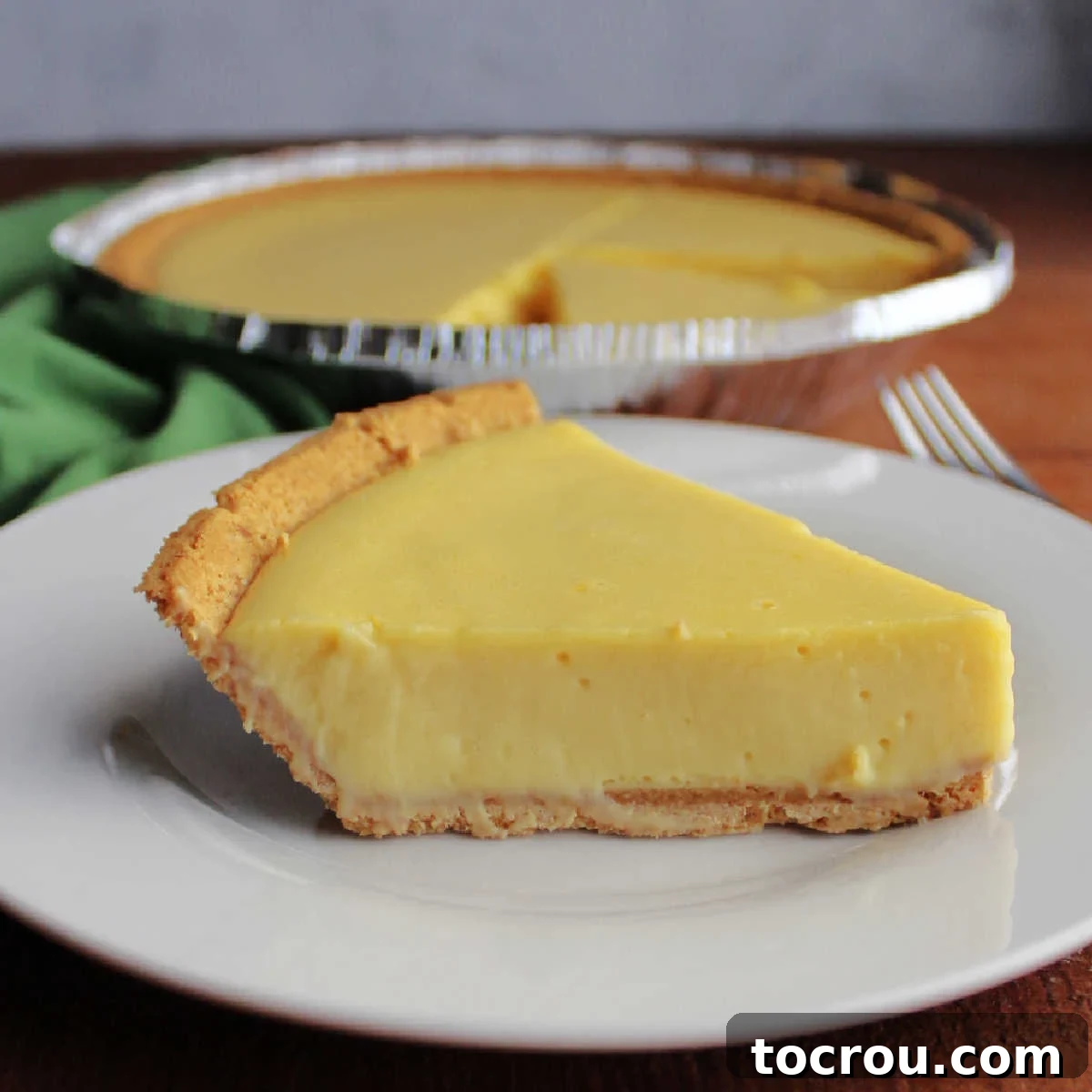 Side view of a perfectly sliced key lime pie, revealing its smooth, creamy, and vibrant green filling nestled in a golden-brown graham cracker crust, ready to be enjoyed.