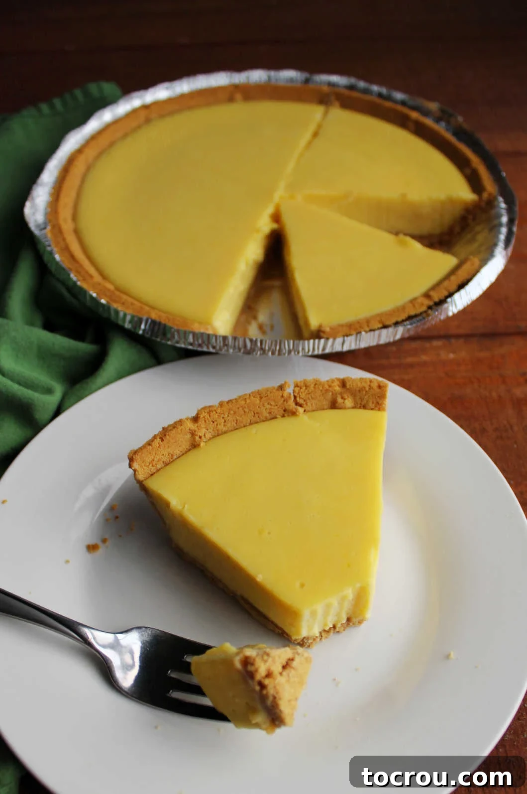 A delicious bite of creamy condensed milk key lime pie, held delicately on a fork, showcasing the vibrant green filling and a hint of the graham cracker crust, ready to be savored.