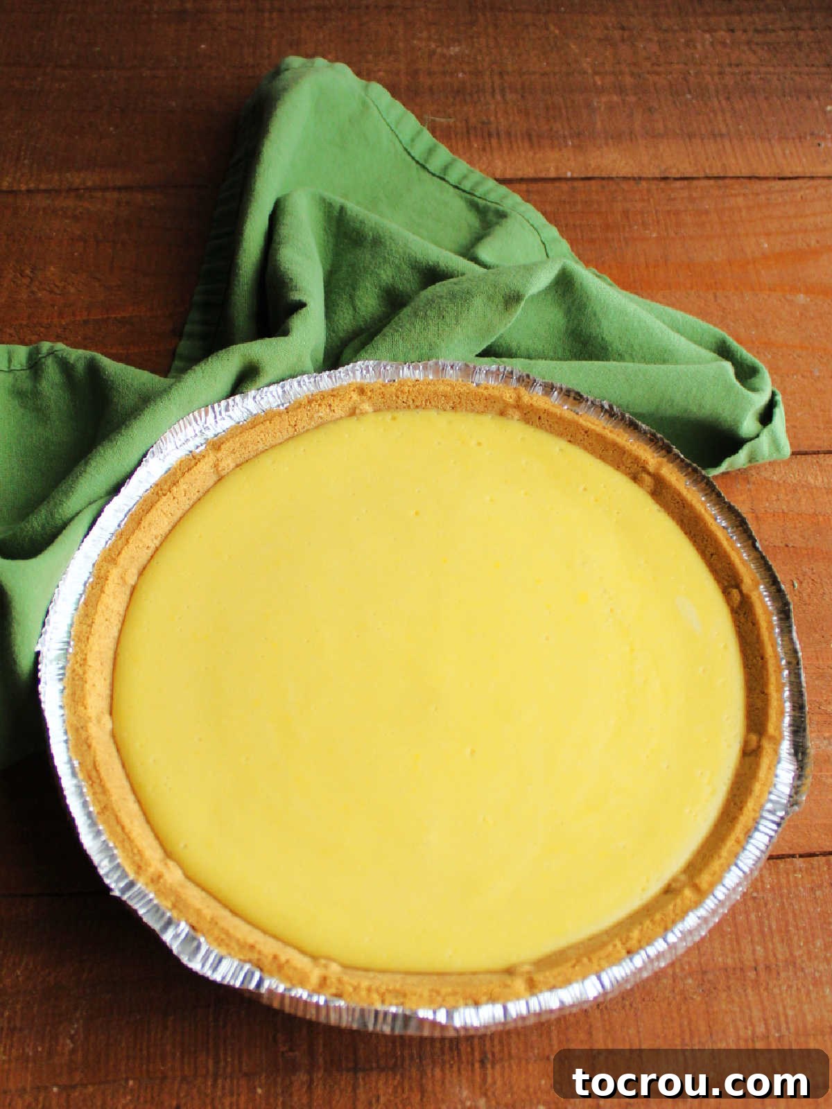 A freshly baked condensed milk key lime pie, just removed from the oven, showcasing its lightly golden edges and set, creamy filling, now ready to be chilled to perfection.