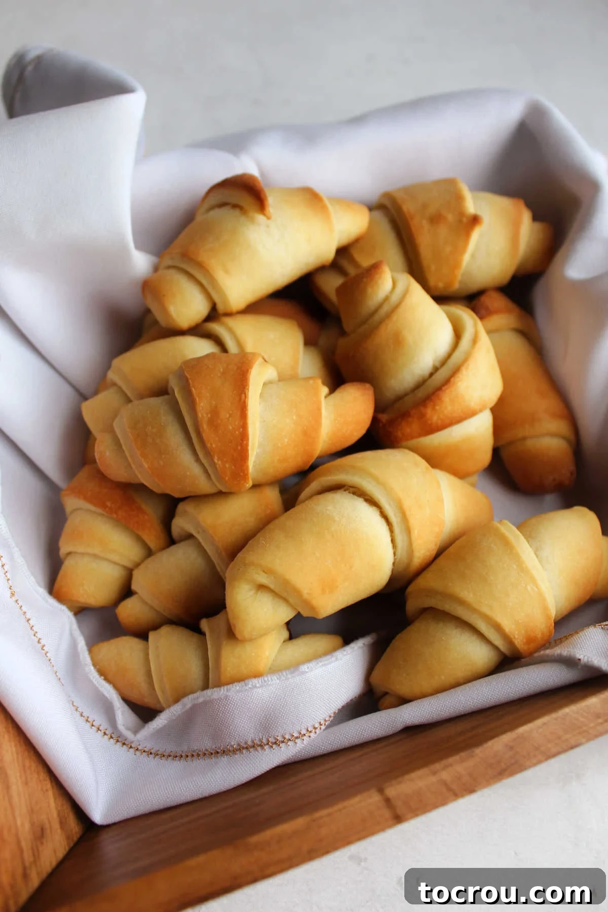 Buttery golden brown homemade crescent rolls in basket, ready to eat.