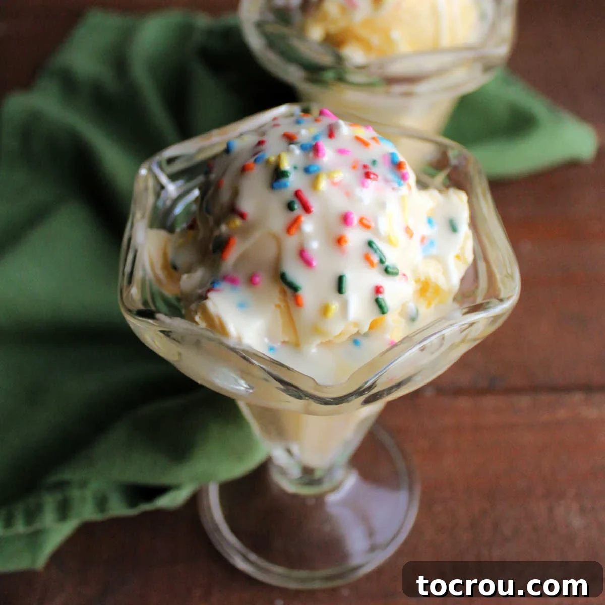 DIY Unicorn Rainbow Glaze 2 Sundae cup filled with vanilla ice cream topped with a hard shell of white chocolate and colorful sprinkles, ready to eat.