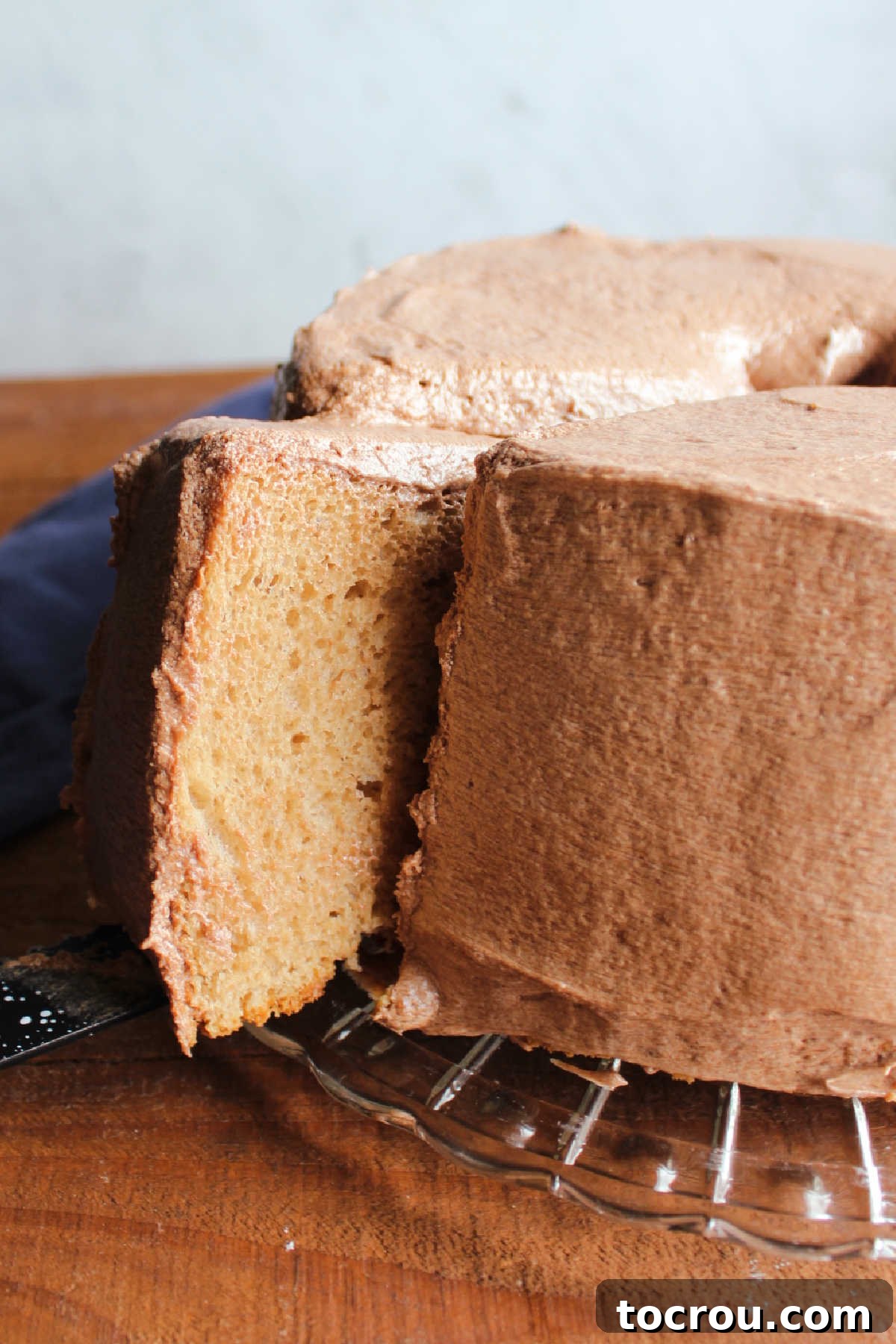 Removing first slice of coffee angel food cake from the cake, showing the light and airy texture inside.