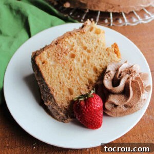 Dessert plate with large slice of coffee angel food cake, a swirl of mocha boiled milk frosting and a strawberry.