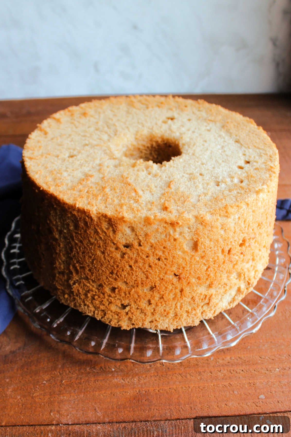 Cooled coffee angel food cake out of the pan and on a glass cake plate.
