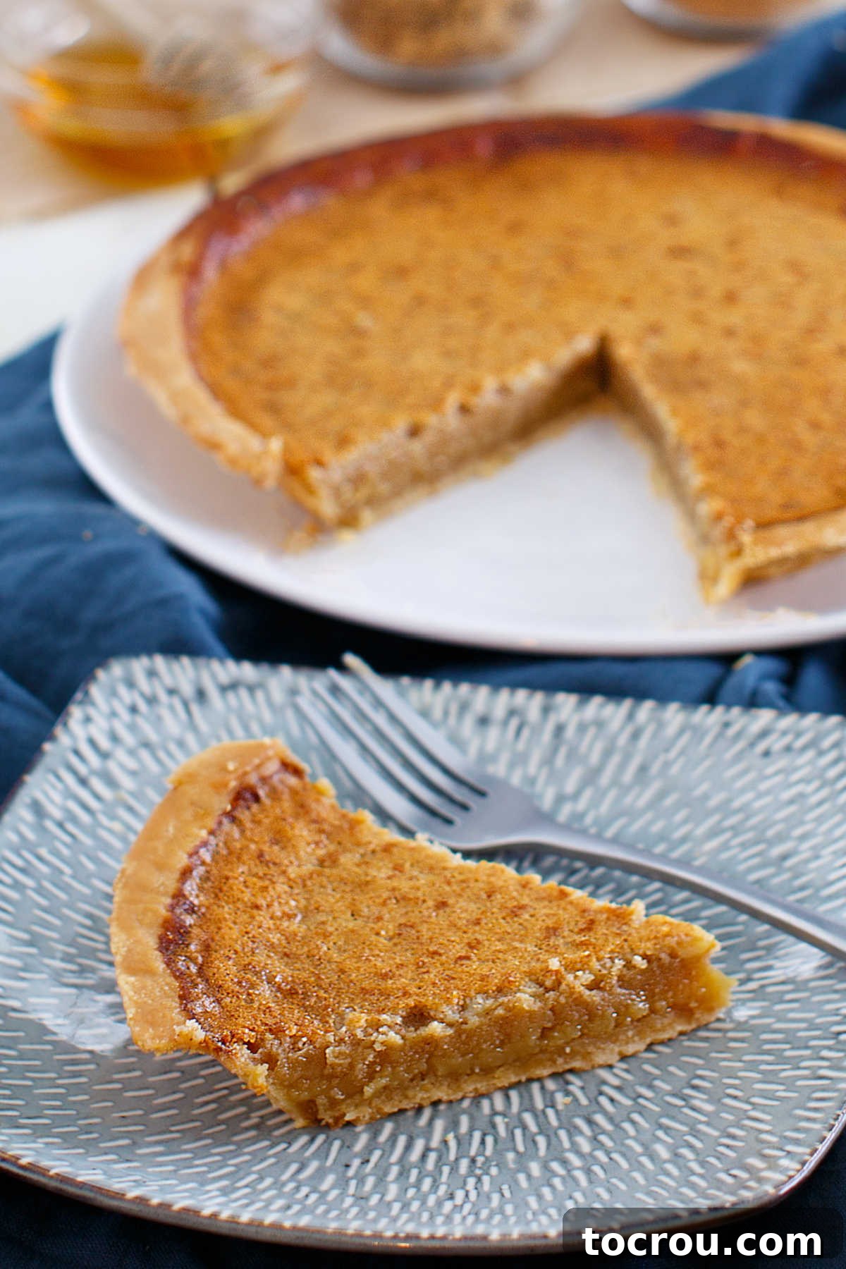 Enjoy this honey sweetened twist on a chess pie. With a kiss of lemon, honey richness and lots of chess pie goodness, it is a perfect treat for almost any occasion! slice of chess pie sweetened with honey ready to eat.