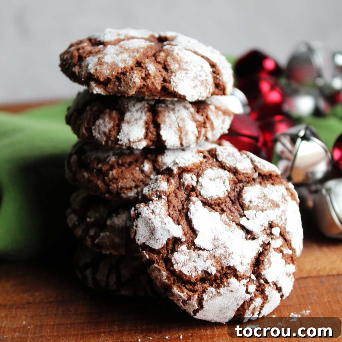 Stack of chocolate crinkles cookies with bits of the chocolate interior showing through the crackled powdered sugar exterior.