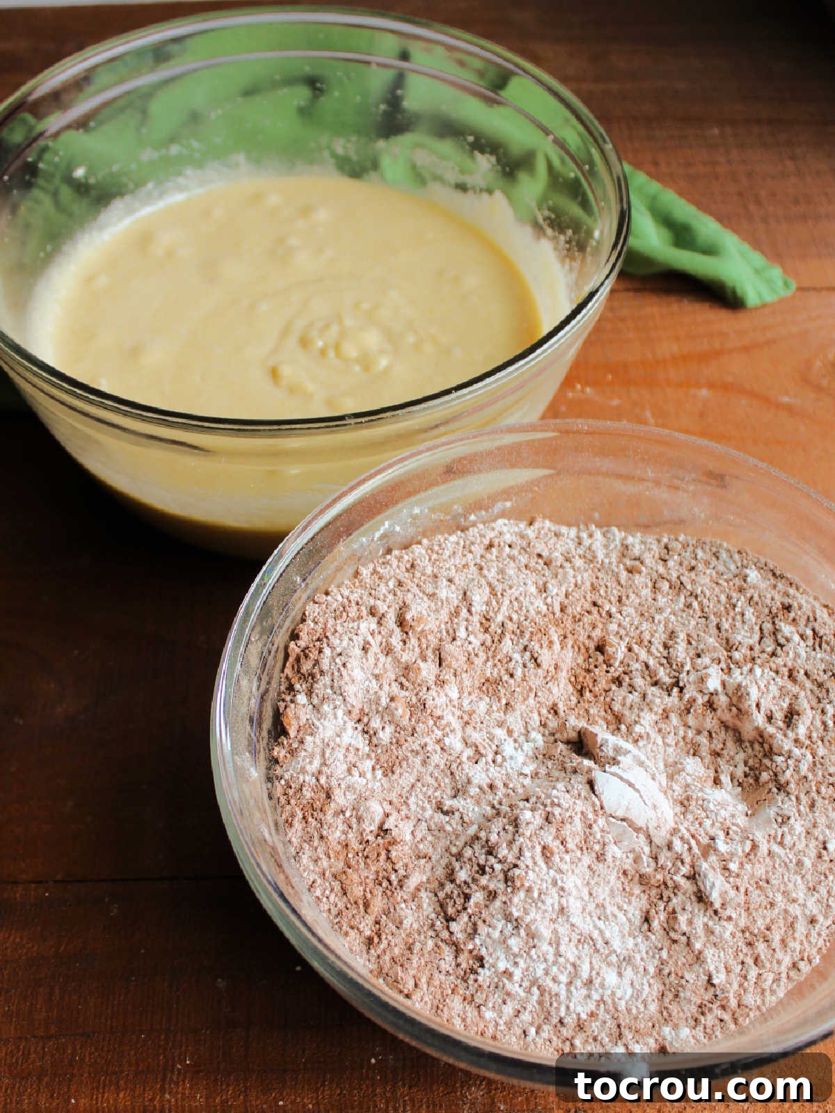 Two mixing bowls, one with the butter, eggs, and sugar mixture and the other with the dry ingredients, ready to be mixed together to make the cookie dough.