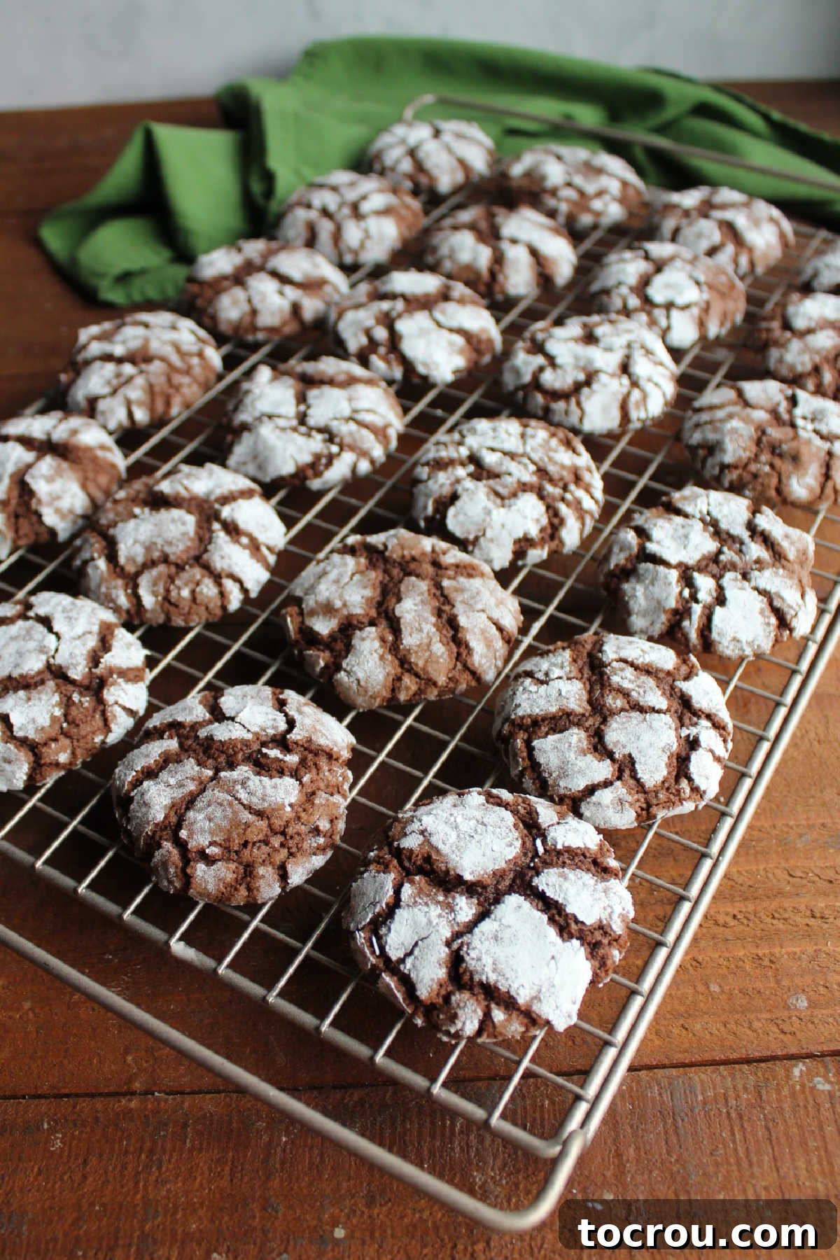 Freshly baked chocolate crinkle cookies cooling on wire rack.