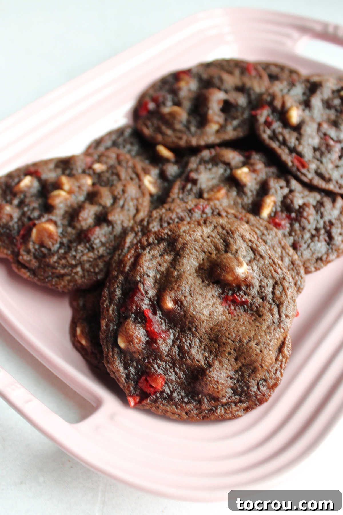 A platter of delicious cookies. A vibrant pink platter generously filled with perfectly baked chocolate cherry cookies, ready for serving or sharing.