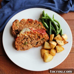 Dinner plate with two slices of Italian sausage meatloaf, roasted potatoes, and roasted green beans.
