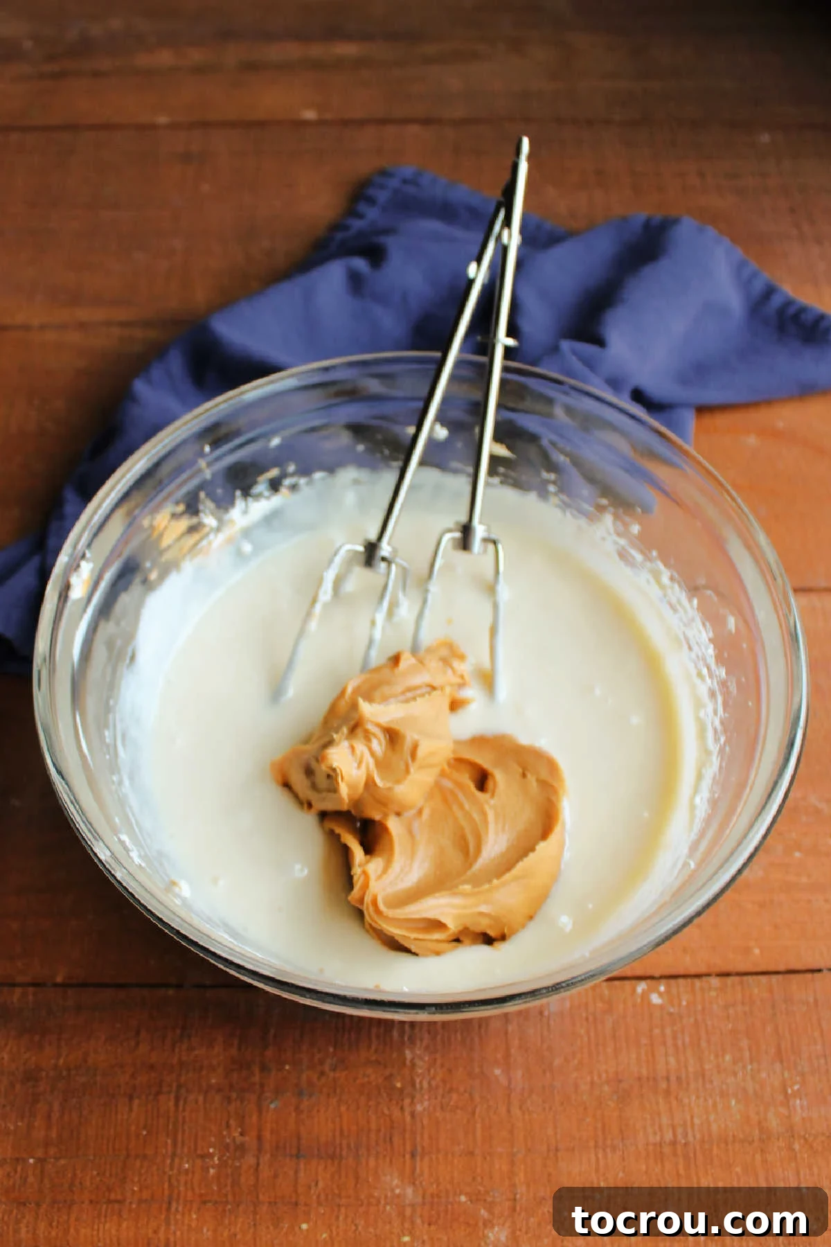 Adding peanut butter to cream cheese and condensed milk mixture.