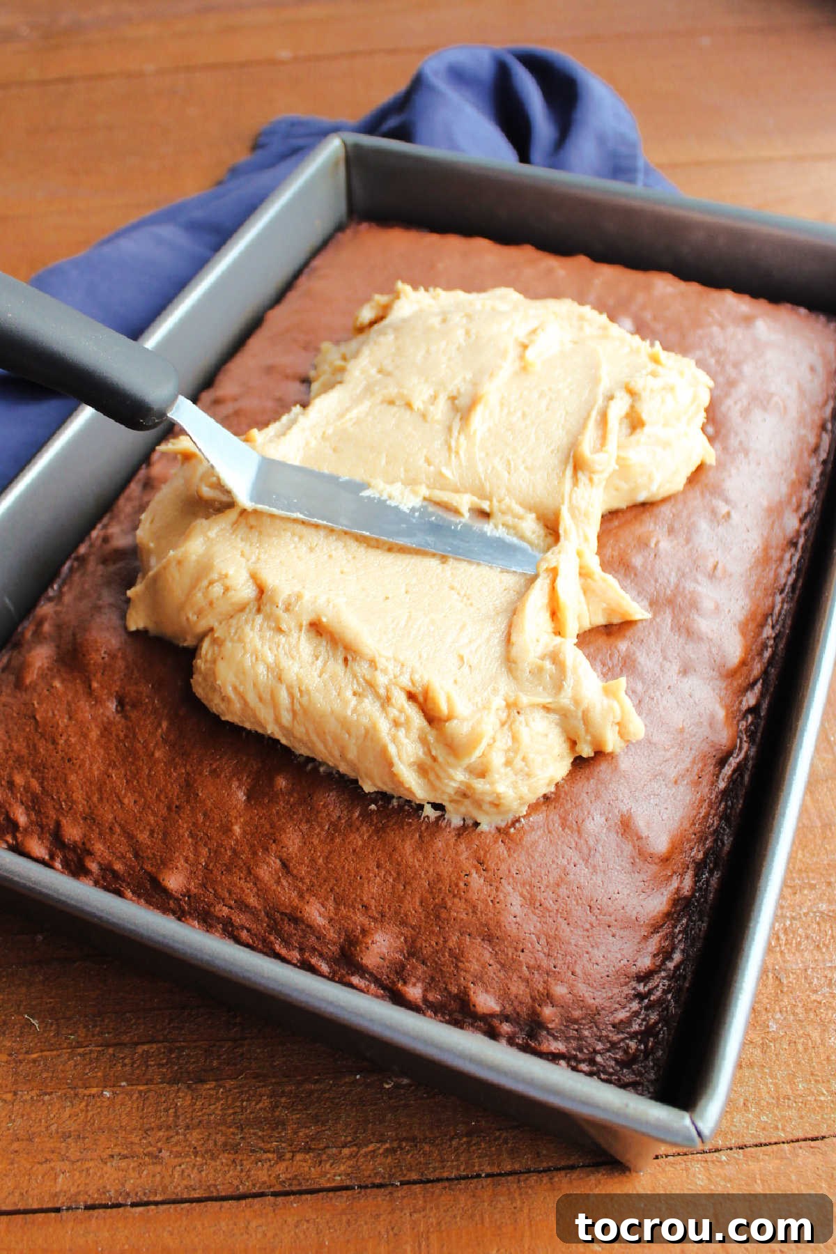 Spreading peanut butter cream cheese frosting over a chocolate cake.