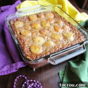 A square baking dish filled with golden banana baked oats, artfully topped with caramelized bananas and a glistening brown sugar mixture.