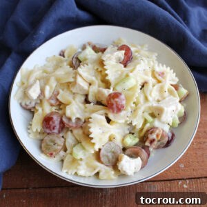 Close up of bowl of poppy seed pasta salad with cream dressing, grapes, celery, and chunks of chicken.