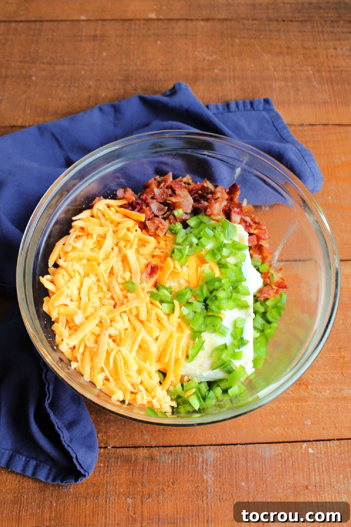 Zingy Bacon Jalapeno Cheese Ball 5 Mixing bowl filled with cream cheese, diced jalapeno peppers, shredded cheddar cheese, and crumbled bacon with seasonings ready to be made into cheese ball.