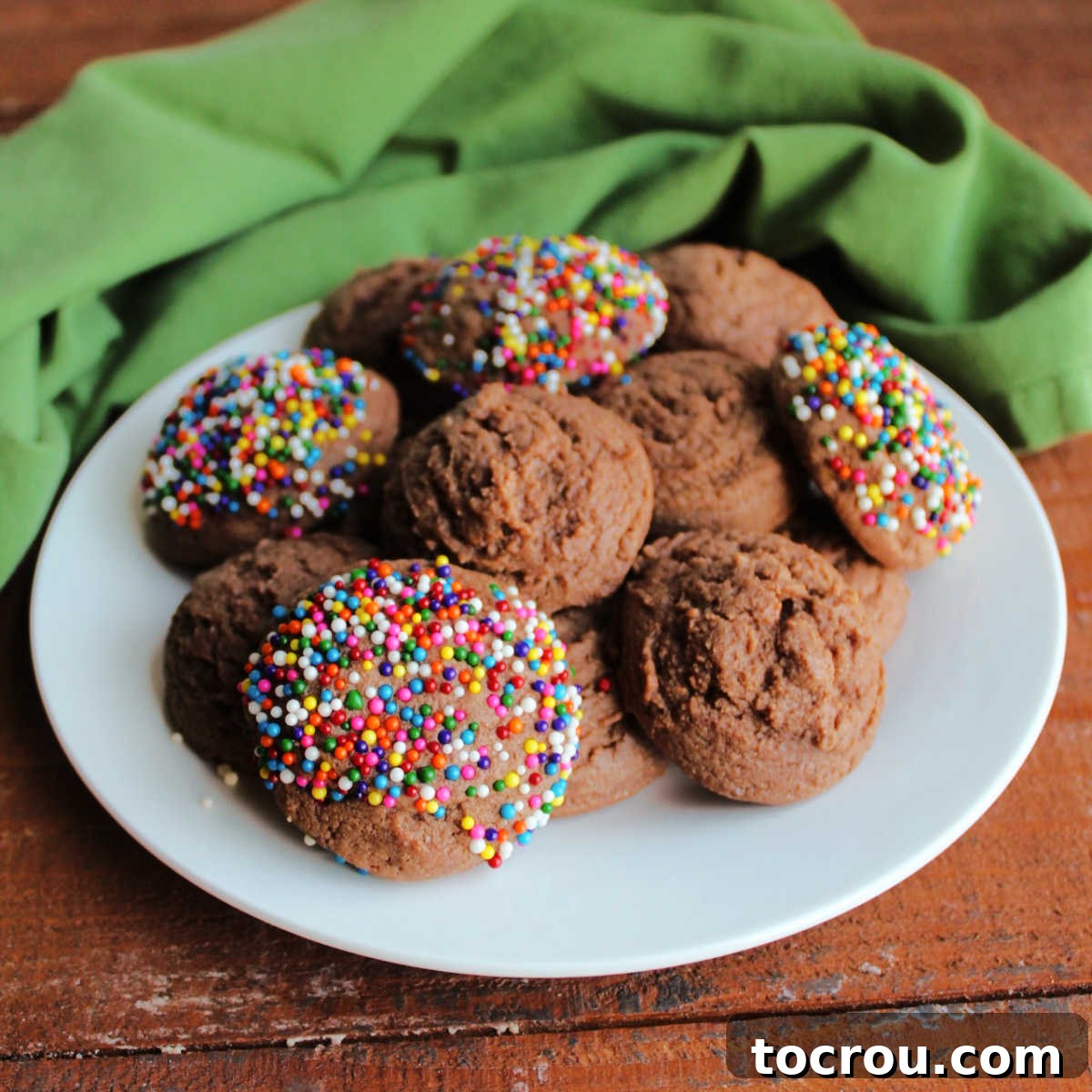 Plate filled with soft, chewy chocolate condensed milk cookies, some plain and others adorned with vibrant colorful sprinkles.