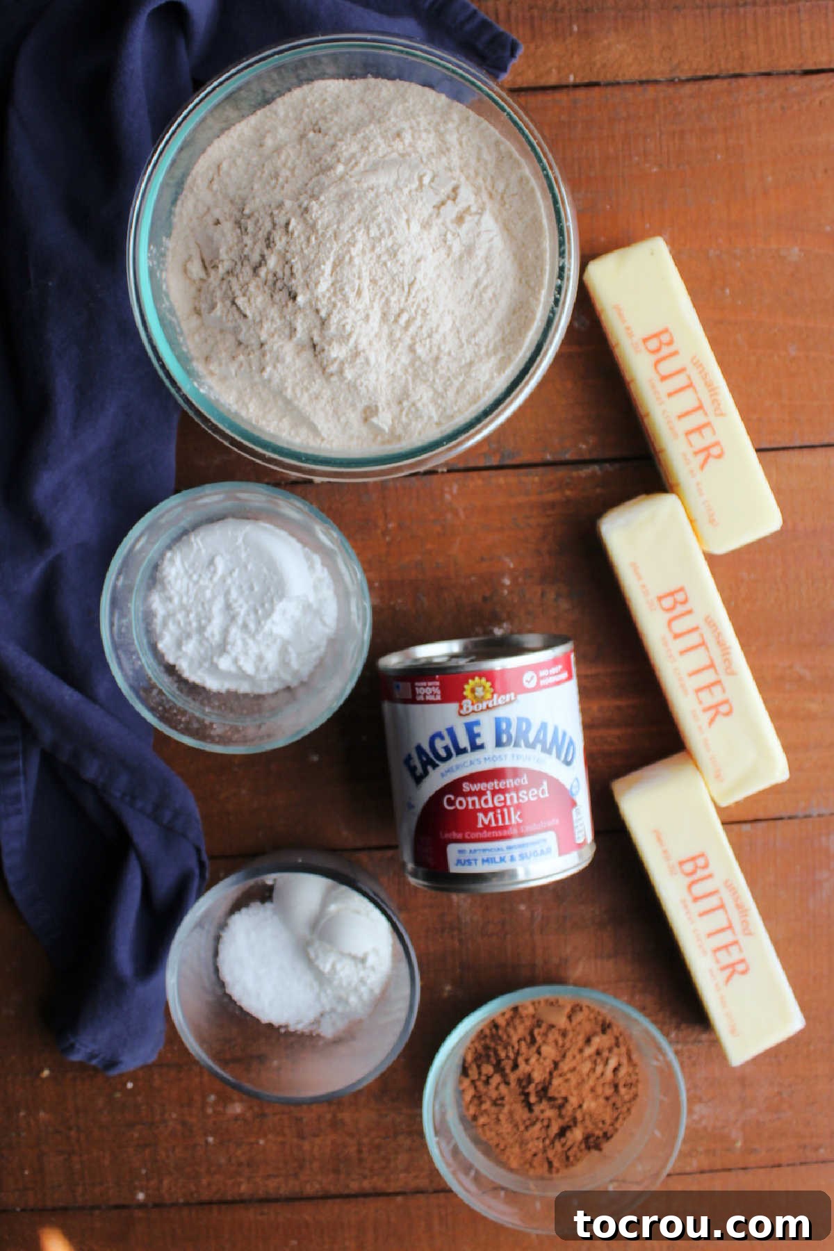 Ingredients for chocolate condensed milk cookies laid out: butter, flour, condensed milk, cocoa powder, salt, powdered sugar, and baking powder.