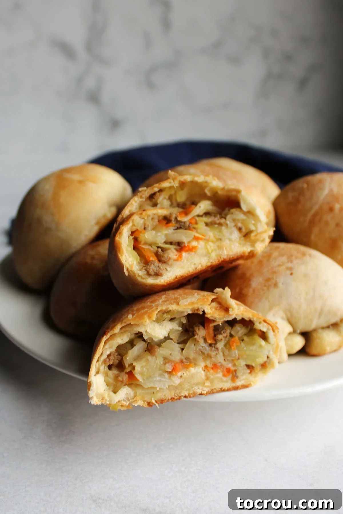 Two beirock halves stack on top of each other showing cooked cabbage, ground beef, and cheese filling.