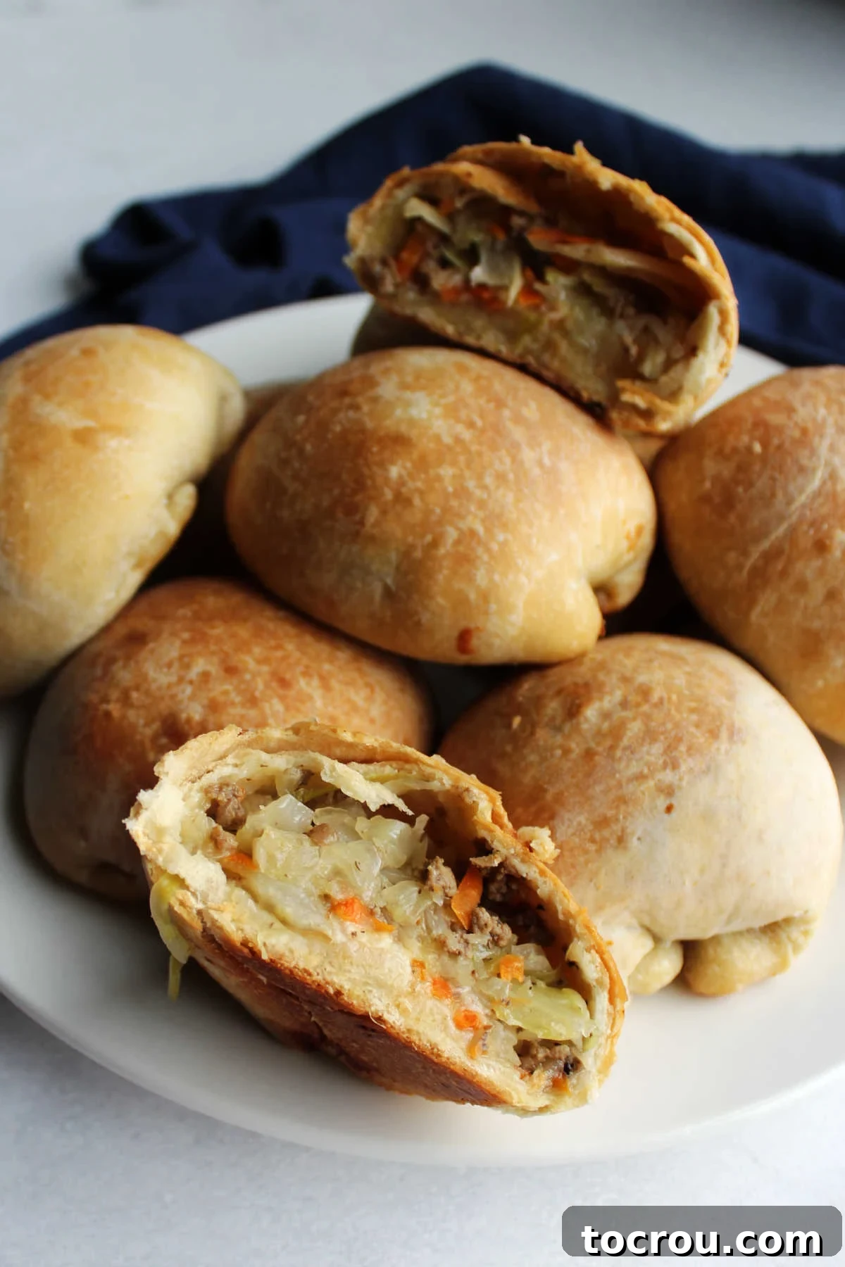 plate of golden brown bierocks filled with cabbage and ground beef, one cut open with the filling showing.