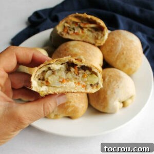 close up of hand holding half of a runza with cabbage and ground beef filling showing.