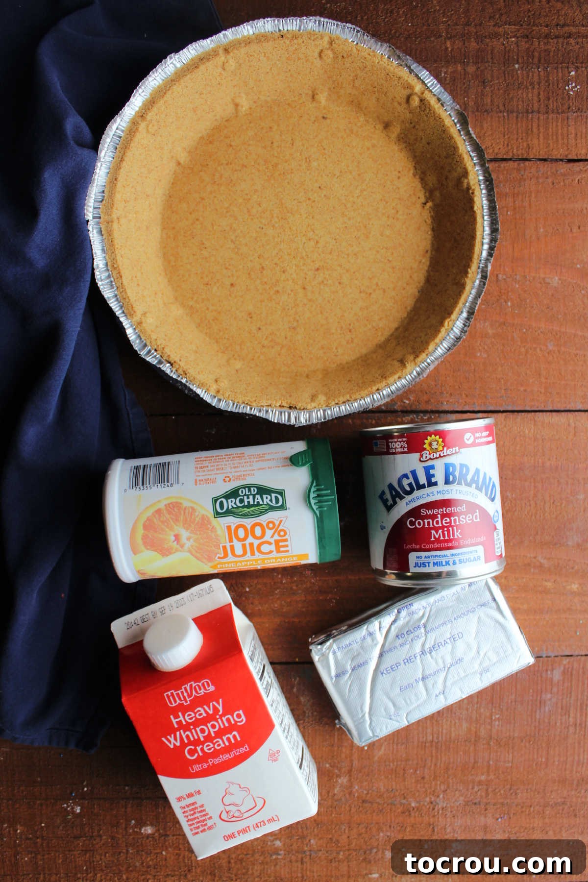 Ingredients including graham cracker crust, cream cheese, condensed milk, heavy cream, and orange juice concentrate.