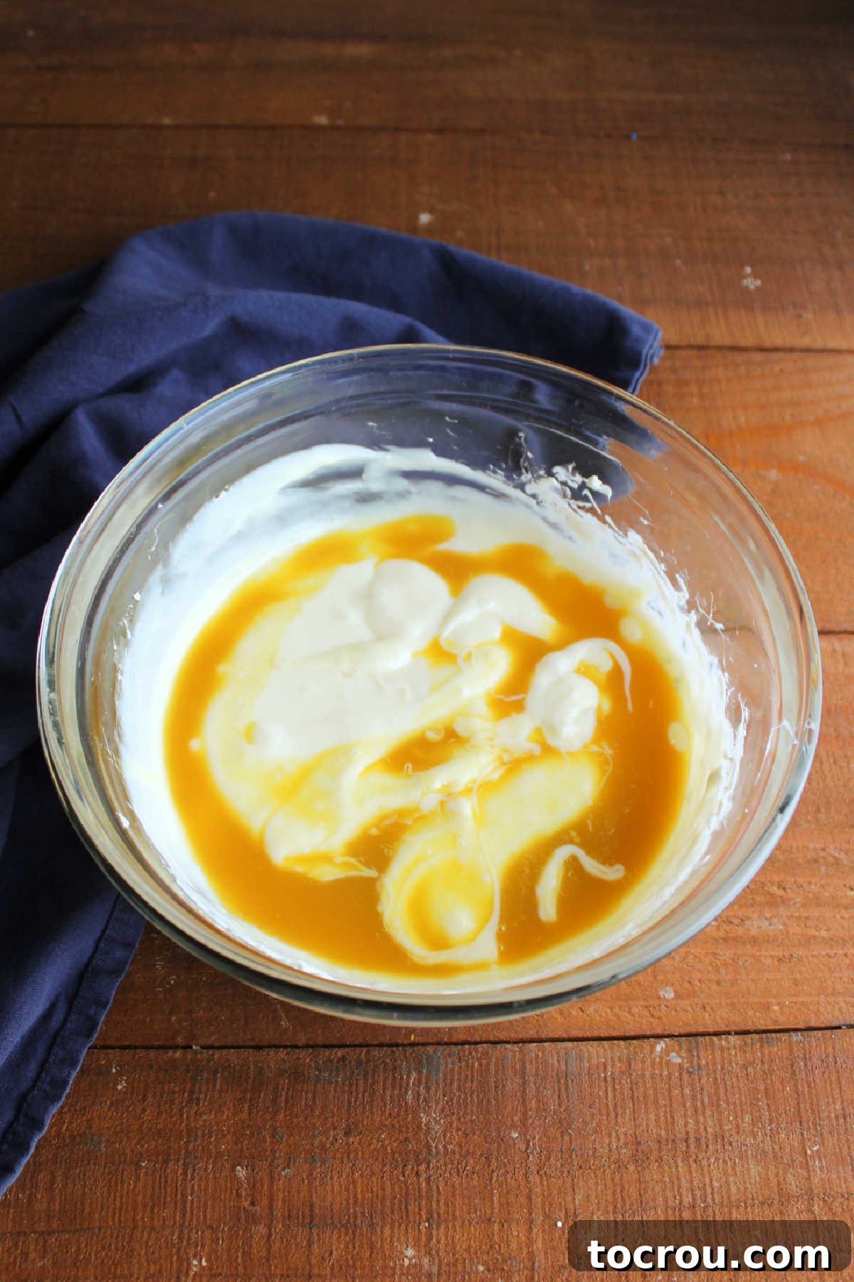 Adding orange juice concentrate to mixing bowl with cream cheese and condensed milk mixture.
