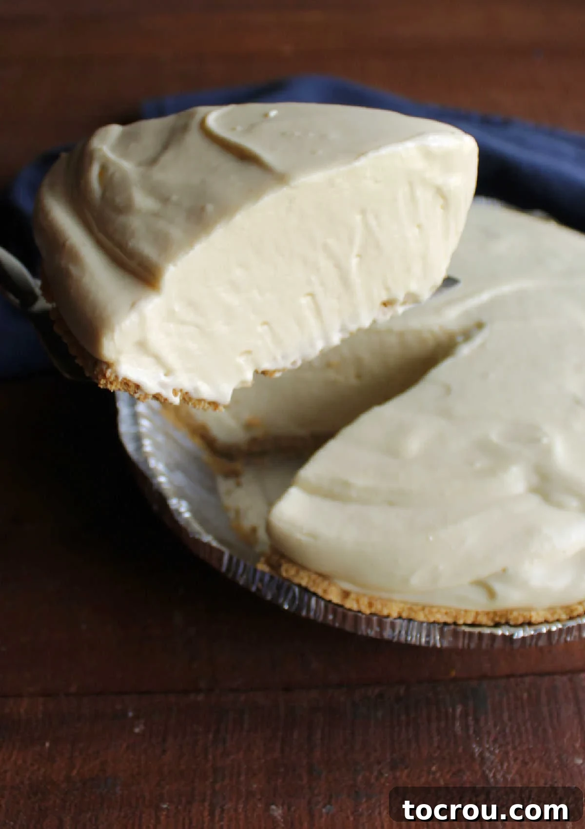 Lifting slice of creamy no bake orange pie out of pie crust.