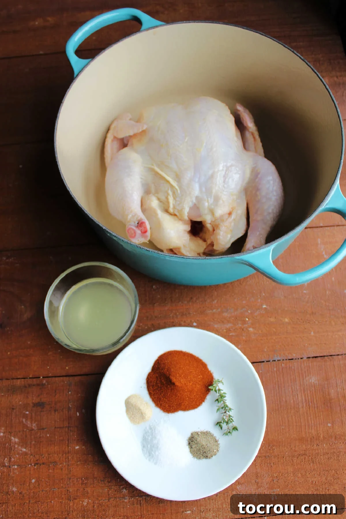 Ingredients including raw chicken, lemon juice, oil, paprika, salt, pepper, garlic powder, and thyme ready to be mixed together and rubbed on chicken. 