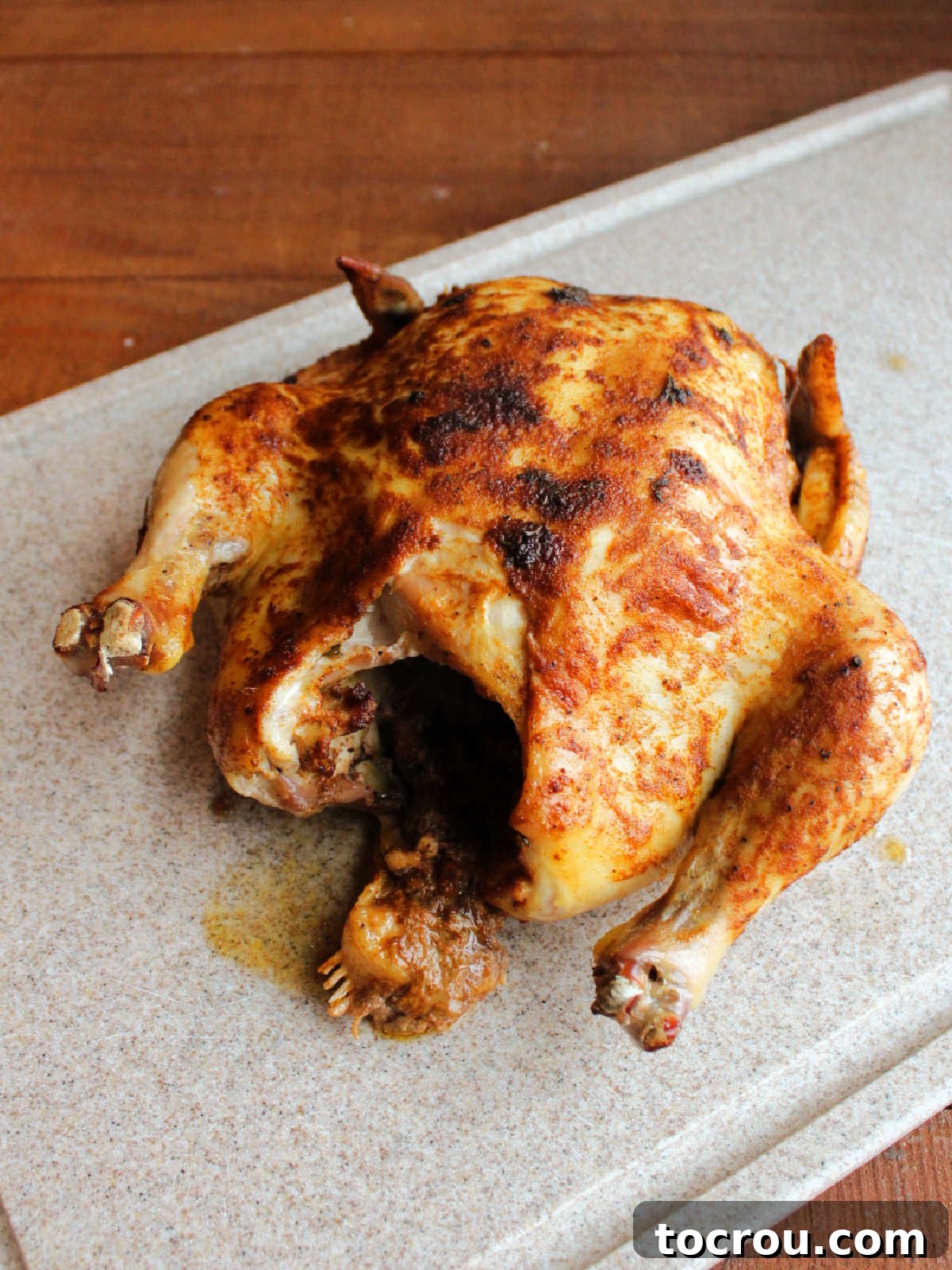 Roasted chicken resting on cutting board before getting carved.