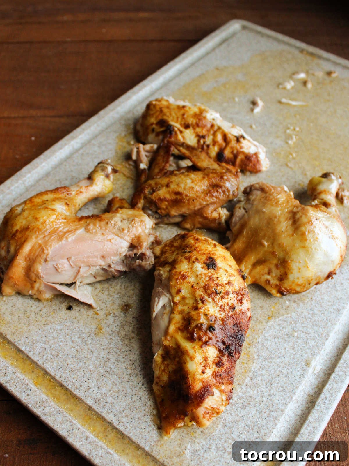 Chicken pieces on cutting board after being carved, showing juicy well seasoned meat.