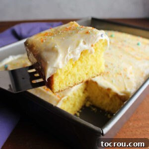 Spatula lifting out piece of lemon cake topped with lemon cream cheese frosting and sprinkles.