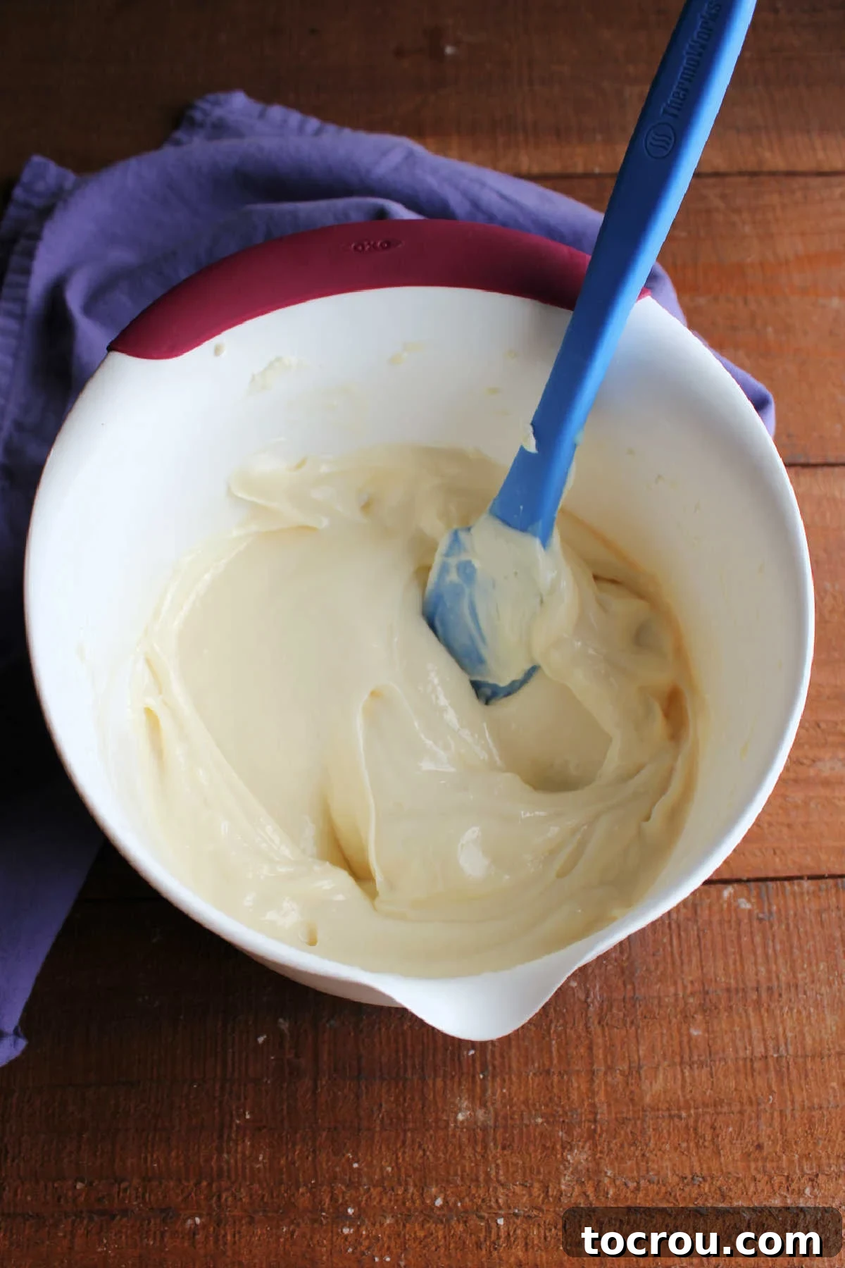 Mixing bowl of chilled lemon cream cheese frosting showing how it is thicker and now holds its ridges when a spatula is run over it.