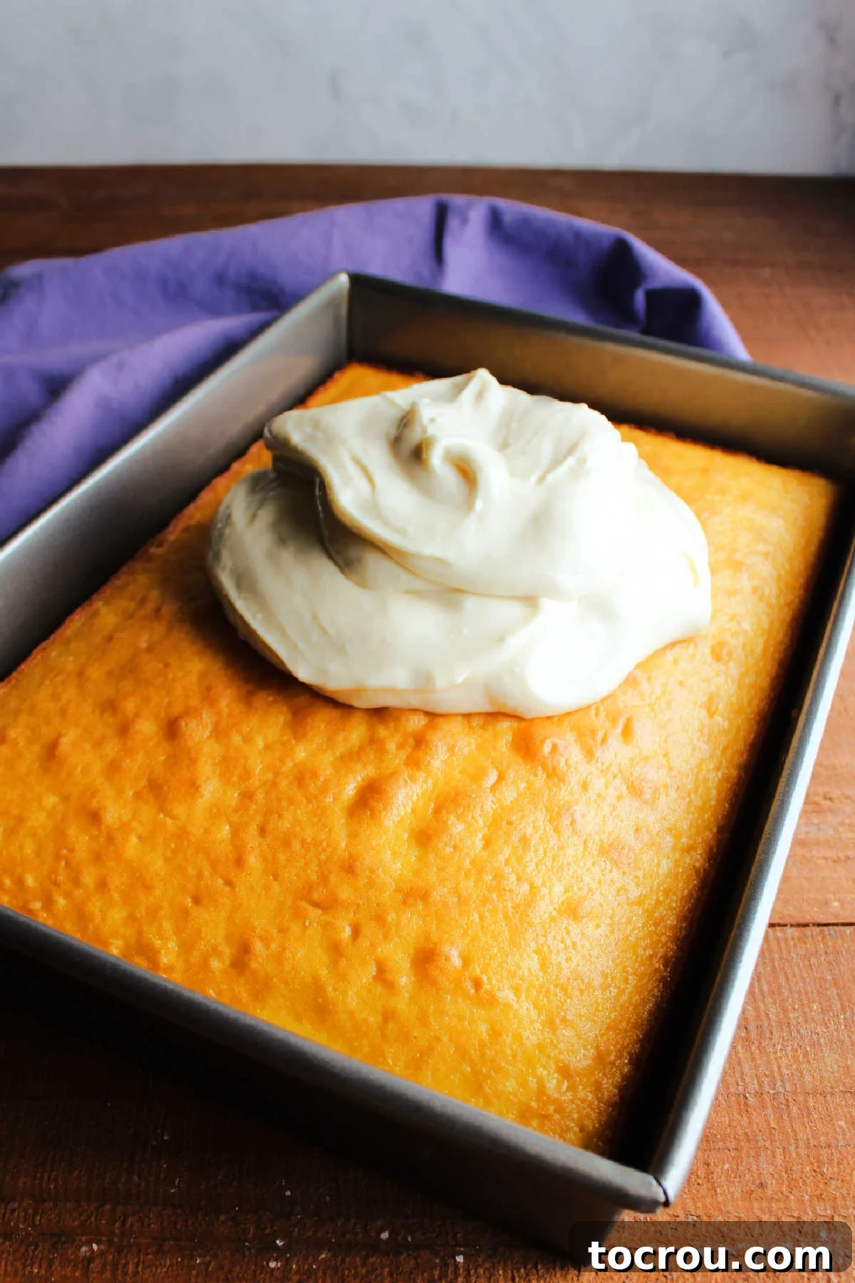 Pile of lemon cream cheese frosting on top of a lemon cake, ready to be spread out.