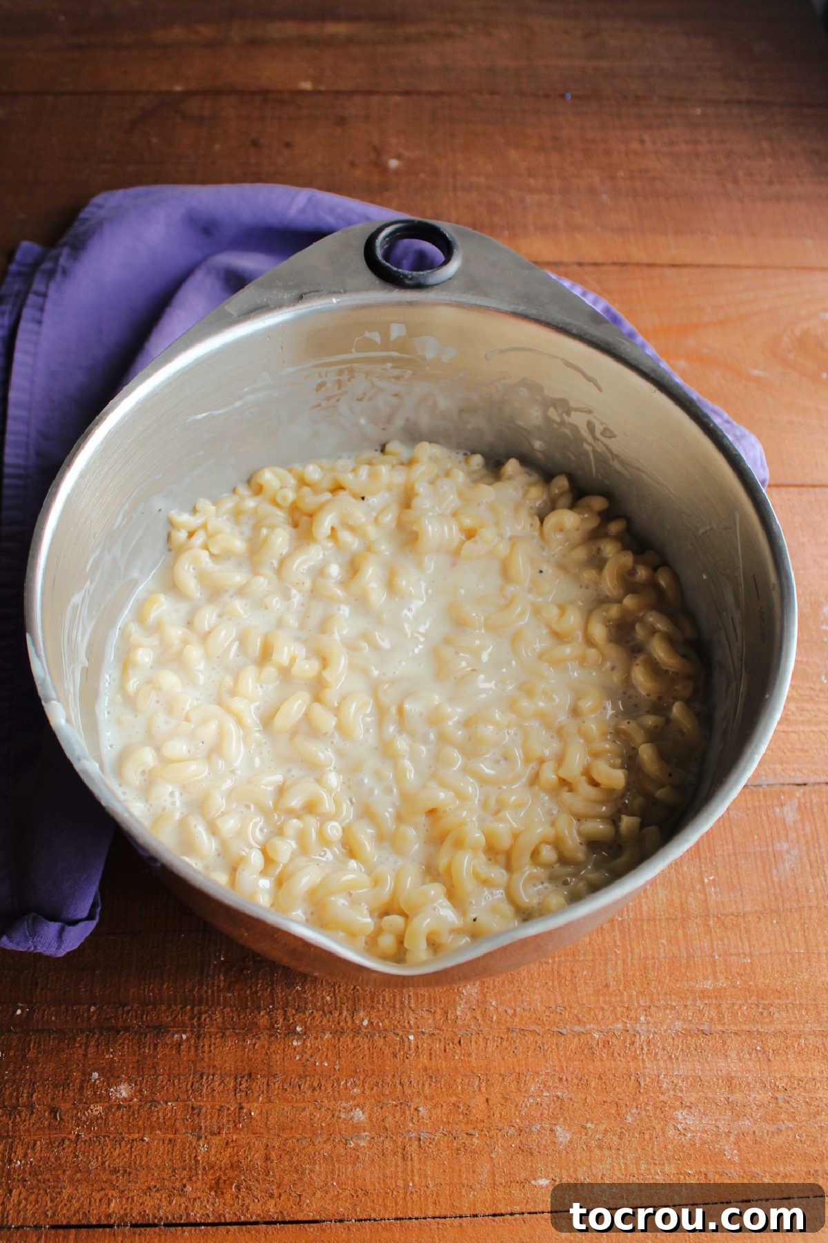 Al dente elbow macaroni noodles stirred into dressing, with lots of dressing still visible.